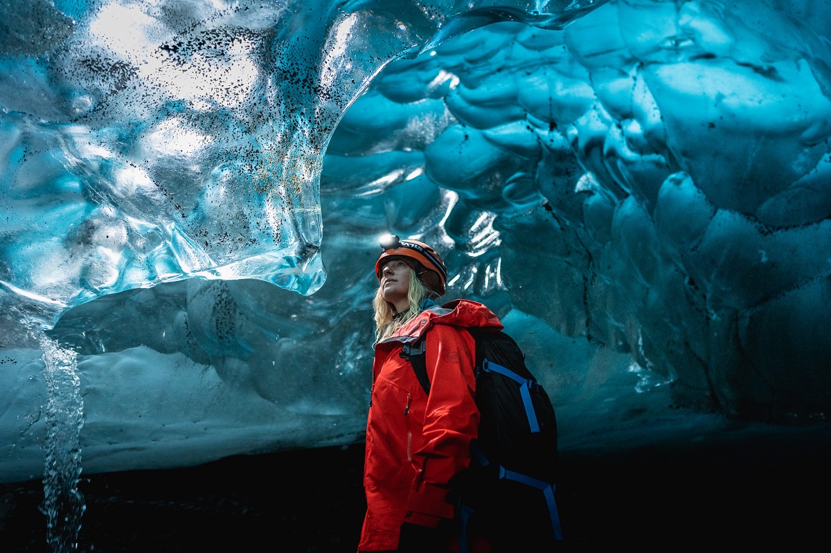 Reiziger in een rode jas in een ijstunnel Vatnajokull | D. Scott Walker - Local Guide of Vatnajokull | IJsland Tours